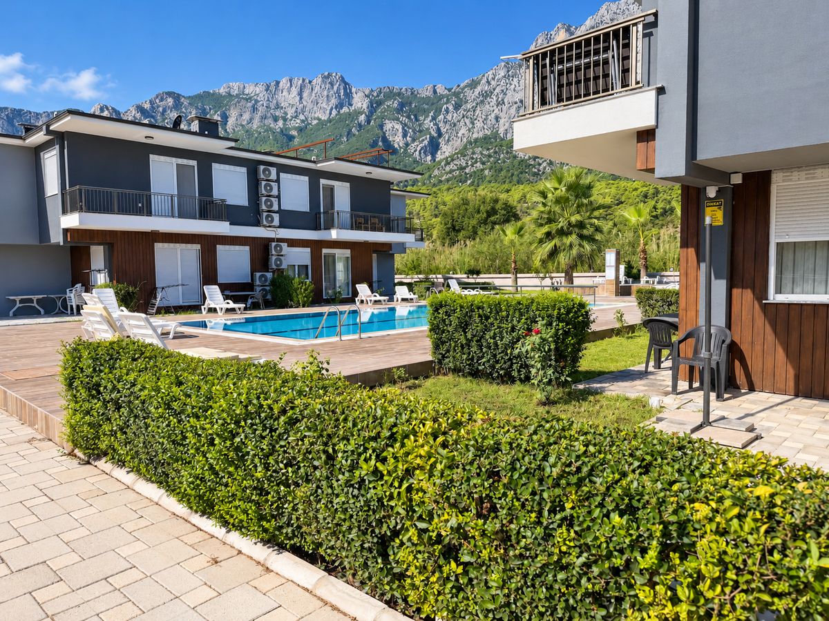 Apartment building with a hedge garden, the pool and the mountains behind