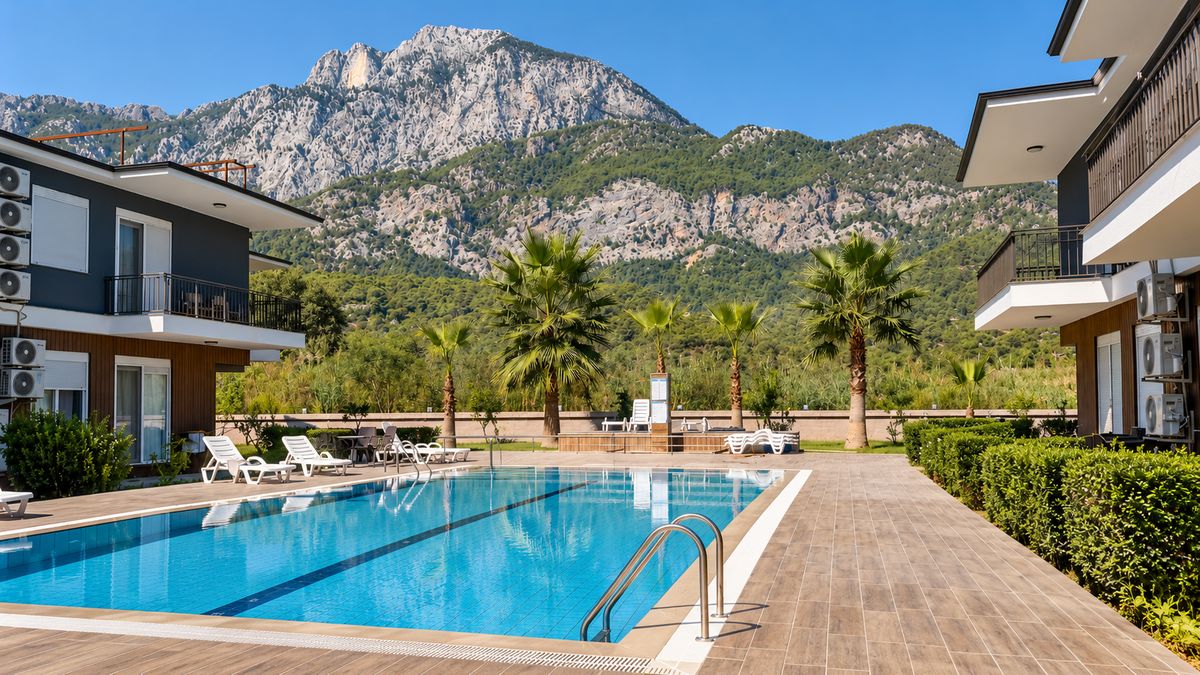 Shared pool in front of the Göynük mountains with palms and the apartment buildings
