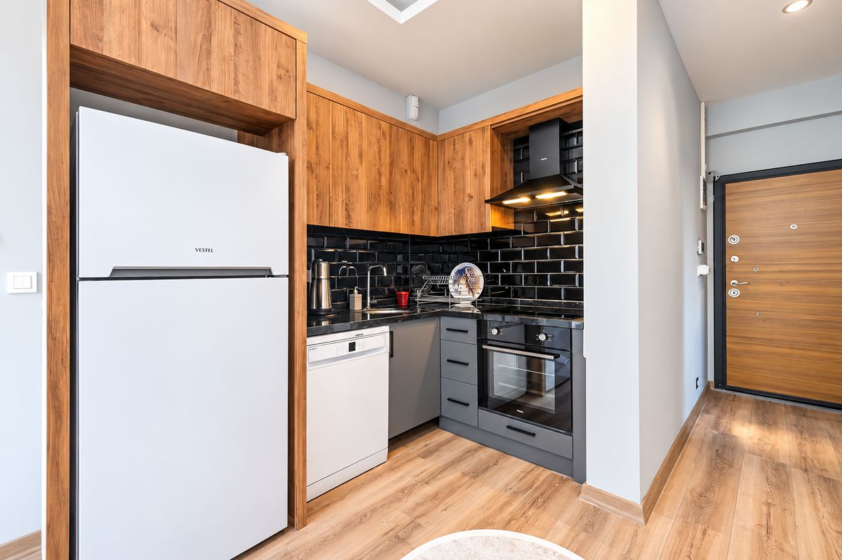Kitchen with wooden cabinets, oven, cooktop, dishwasher and fridge