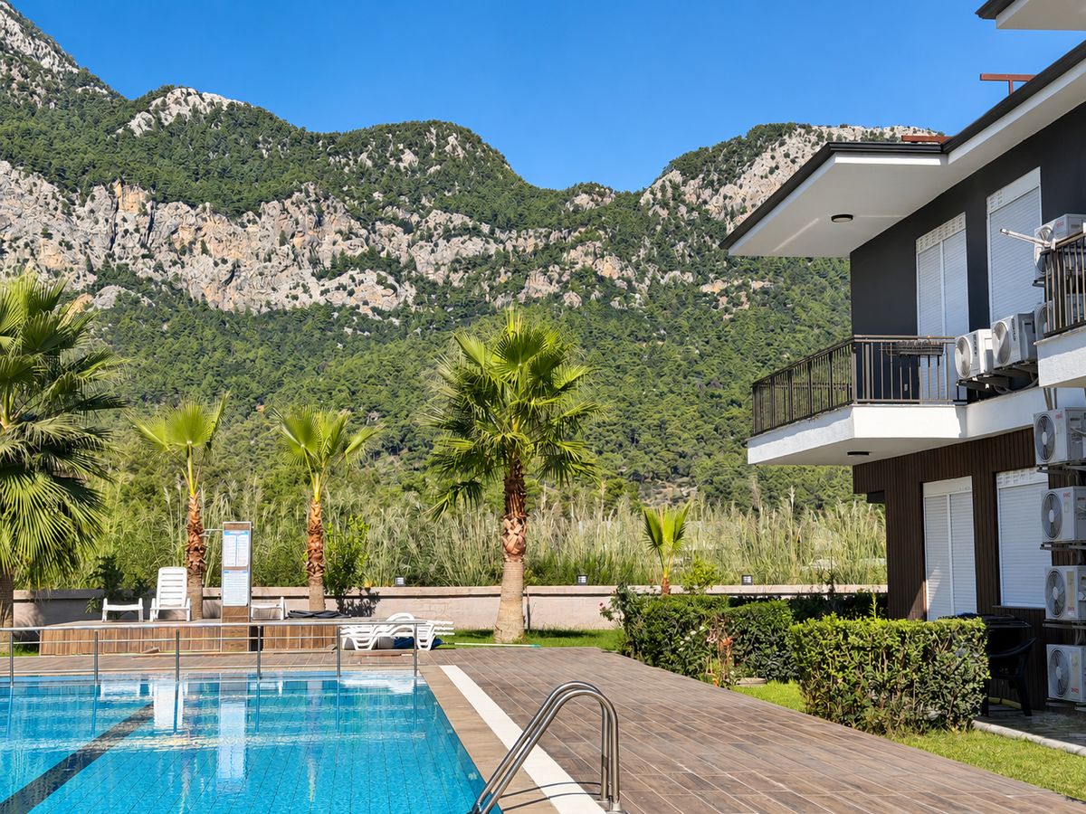 Pool edge with palms, the forested mountain and the apartment building