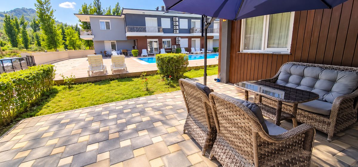 Garden seating under a parasol with the pool in the background
